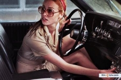 La dame dans l'auto avec des lunettes et un fusil photo from the set.